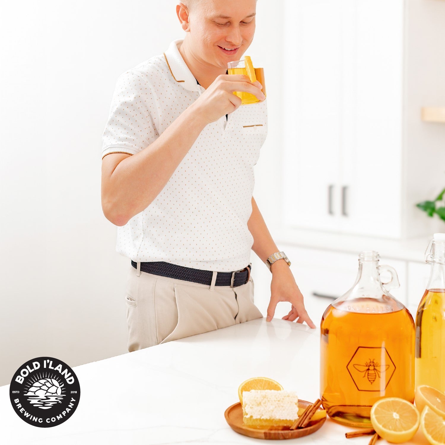 A photo of a young man taking a drink of his batch of mead with a smile on his face.